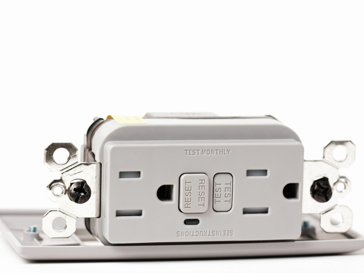 GFCI outlet removed from wall plate for installation.